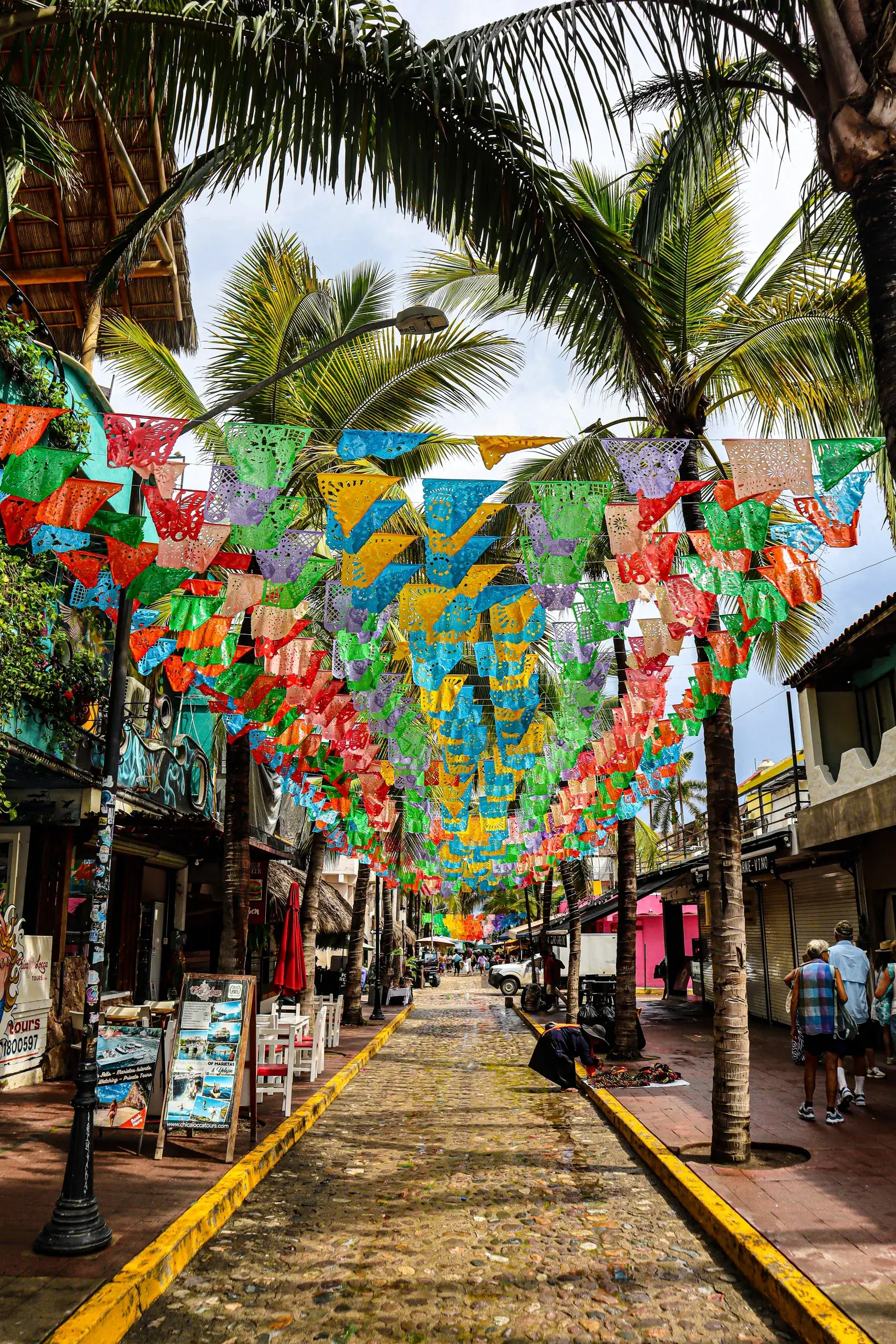 Calle de Sayulita con papel picado entre las palmeras